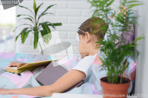 Image of The sick girl lies in bed and fell asleep reading a book