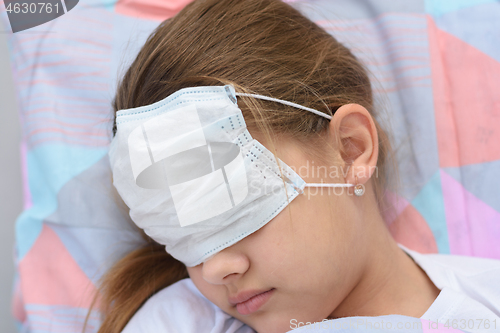 Image of The girl fell asleep in bed, on her face and eyes she pulled on a medical mask, close-up