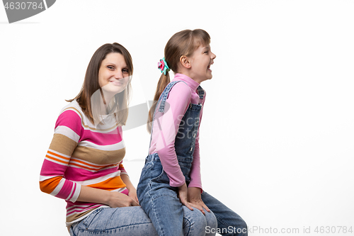 Image of On the mothers lap, a daughter sits and laughs joyfully turning to the side