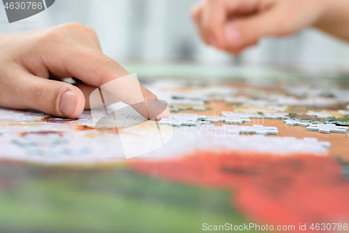 Image of Close-up of children\'s hands collecting jigsaw puzzles