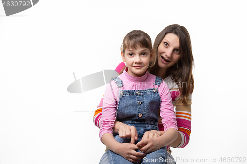 Image of A girl sits on her mothers lap and stares in surprise at the frame