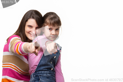 Image of Mom and daughter point a finger at the frame, side empty space in the frame