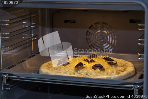 Image of Baking quattro formaggi pizza in oven with open door.