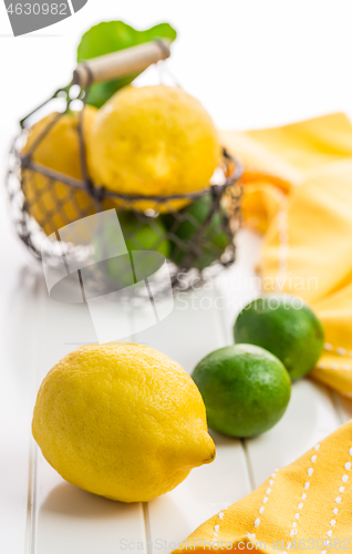 Image of Organic lemons and limes in a basket on white background