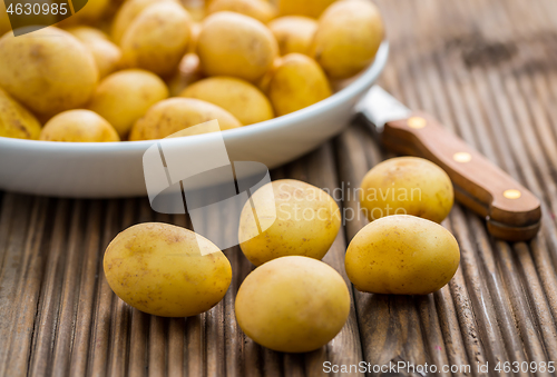 Image of Fresh organic small potatoes in bowl with knife on wooden background