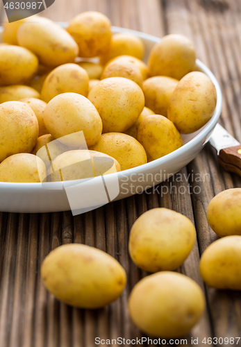 Image of Fresh organic small potatoes in bowl with knife on wooden background