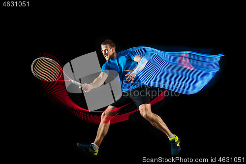 Image of one caucasian man playing tennis player on black background