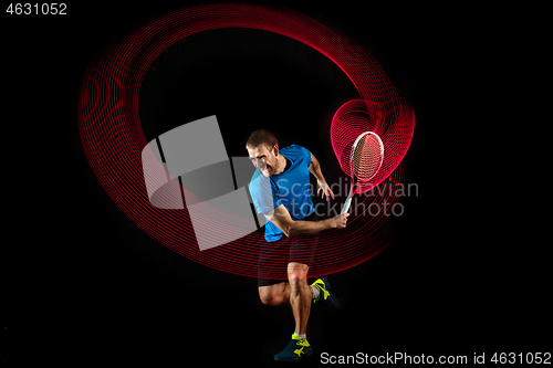 Image of one caucasian man playing tennis player on black background