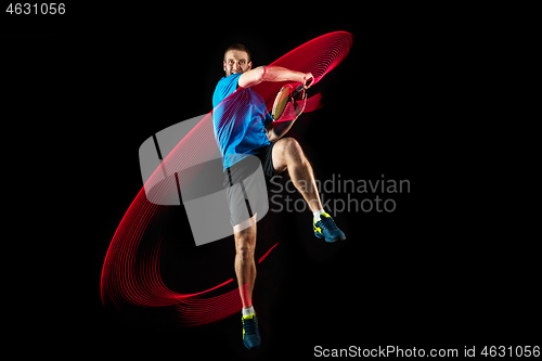 Image of one caucasian man playing tennis player on black background