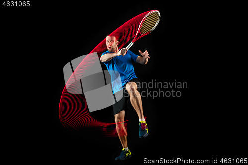 Image of one caucasian man playing tennis player on black background