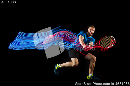 Image of one caucasian man playing tennis player on black background