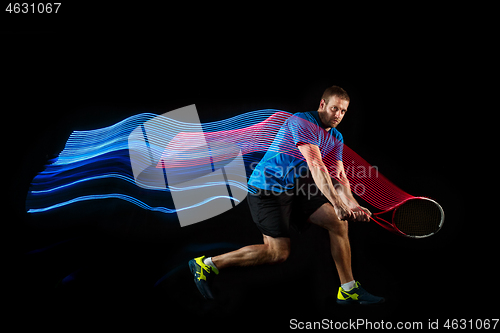 Image of one caucasian man playing tennis player on black background