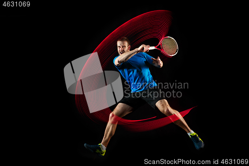 Image of one caucasian man playing tennis player on black background