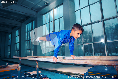 Image of beautiful boy is engaged in sports gymnastics on a parallel bars