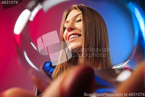 Image of The surprised young woman in party clothes posing with glass of wine.