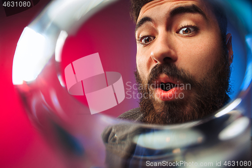 Image of The surprised young man in party clothes posing with glass of wine.