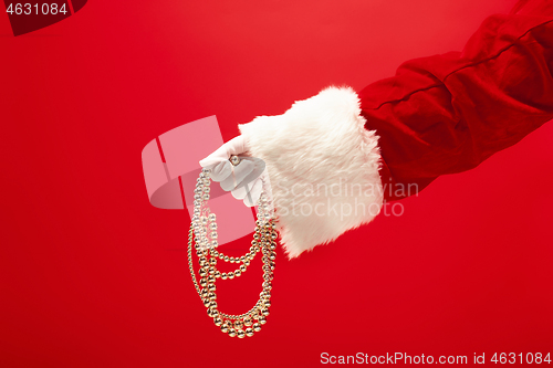 Image of Hand of Santa Claus holding a toy Christmas decorations on red background