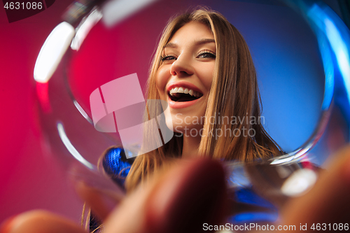 Image of The surprised young woman in party clothes posing with glass of wine.