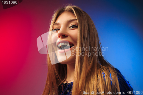 Image of The happy woman standing and smiling against colored background.