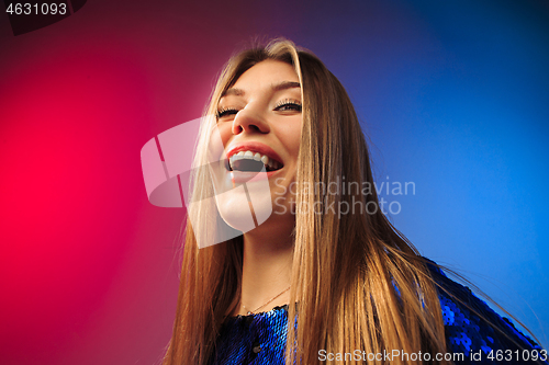 Image of The happy woman standing and smiling against colored background.