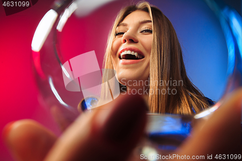 Image of The surprised young woman in party clothes posing with glass of wine.