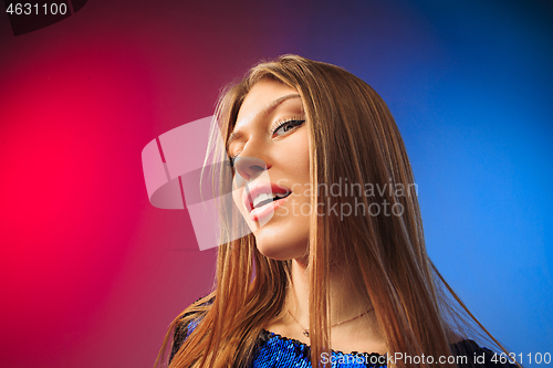 Image of The happy woman standing and smiling against colored background.