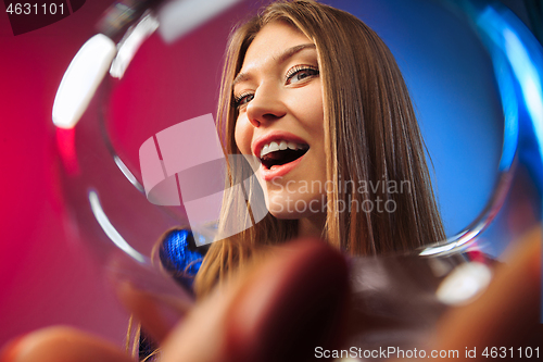 Image of The surprised young woman in party clothes posing with glass of wine.