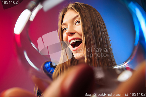 Image of The surprised young woman in party clothes posing with glass of wine.