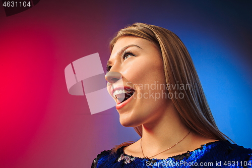 Image of The happy woman standing and smiling against colored background.