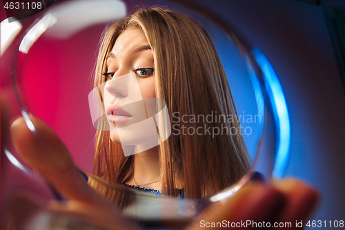 Image of The surprised young woman in party clothes posing with glass of wine.