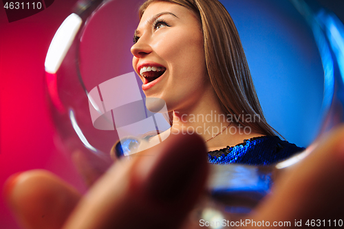 Image of The surprised young woman in party clothes posing with glass of wine.