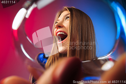 Image of The surprised young woman in party clothes posing with glass of wine.