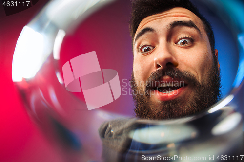 Image of The surprised young man in party clothes posing with glass of wine.