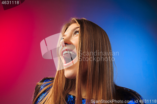 Image of The happy woman standing and smiling against colored background.