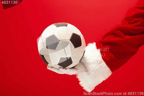 Image of Santa Claus holding a football ball isolated on red background