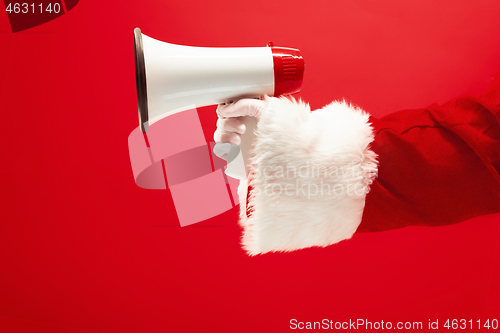 Image of Hand of Santa Claus holding a megaphone on red background