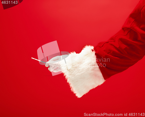 Image of Hand of Santa Claus holding a pregnancy test on red background