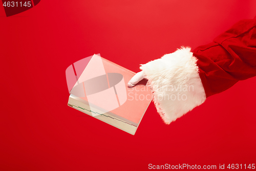 Image of Hand of Santa Claus holding a notebook on red background