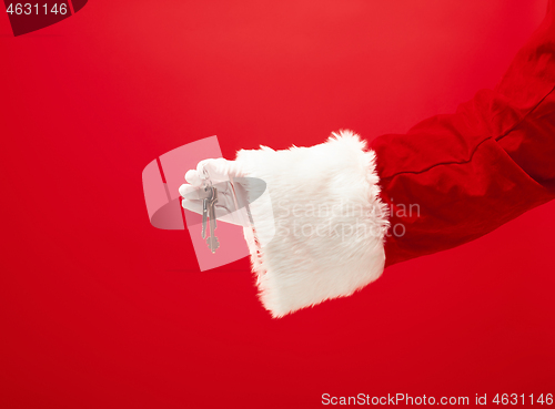 Image of Hand of Santa Claus holding a gift on red background