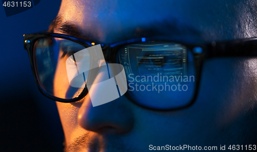 Image of close up of hacker in glasses looking at screen