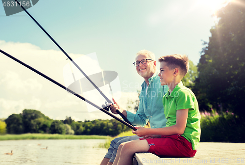 Image of grandfather and grandson fishing on river berth