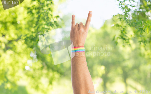 Image of hand with gay pride rainbow wristband shows rock