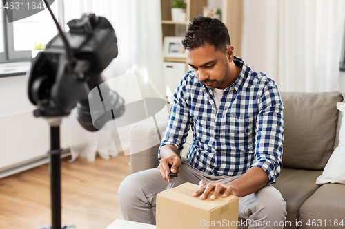Image of male video blogger opening parcel box at home