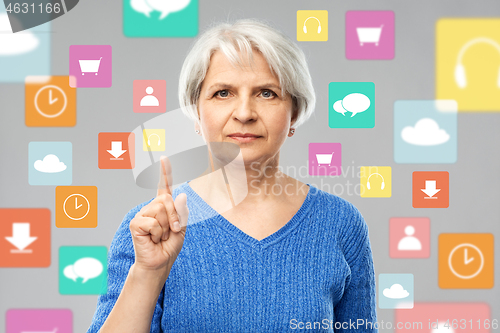 Image of senior woman pointing finger up over app icons