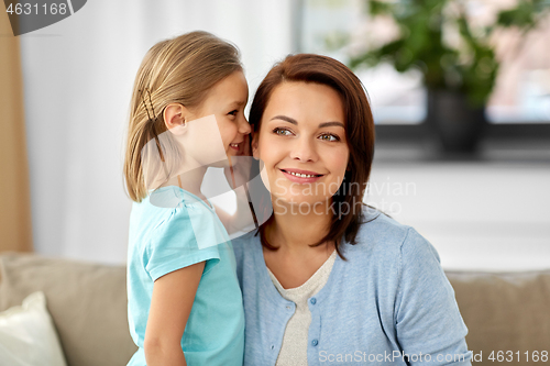 Image of daughter whispering secret to mother at home