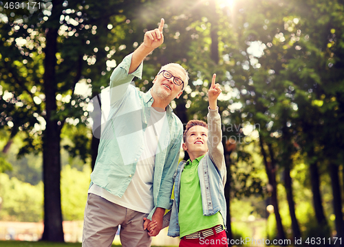 Image of grandfather and boy pointing up at summer park