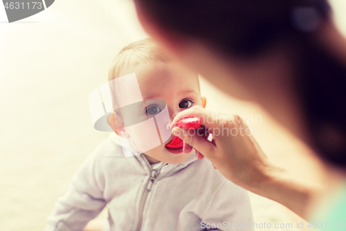 Image of mother with spoon feeding little baby at home