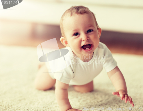 Image of little baby in diaper crawling on floor at home