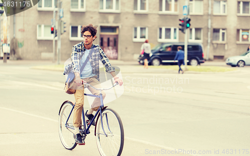 Image of young hipster man with bag riding fixed gear bike