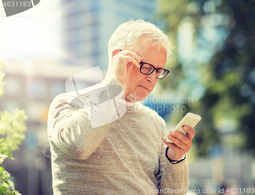 Image of senior man texting message on smartphone in city